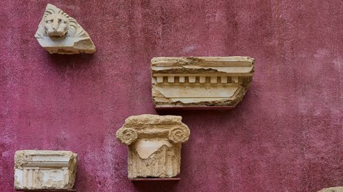 Architectural fragments of stone, ancient marble pieces attached to a wall, outdoor area,
