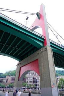 La Salve Bridge, A large bridge with red and green elements towering over buildings and
