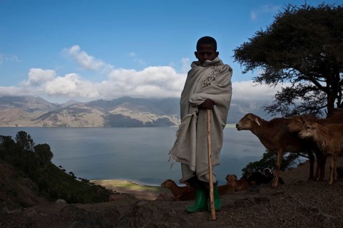 Boy working as a shepherd, Lake Hashenge in the background, Tigray state, Ethiopia. The boy is