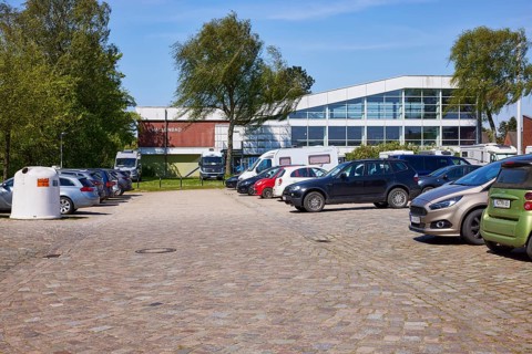 Used glass container, car park and indoor swimming pool in Niebuell, Nordfriesland district,