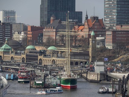 Close-up of a harbour with a sailing ship and historical next to modern buildings, many ships in a