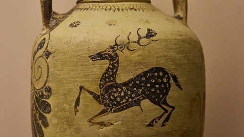 Antique jug with a detailed image of a stag and floral ornaments in black on a beige background,