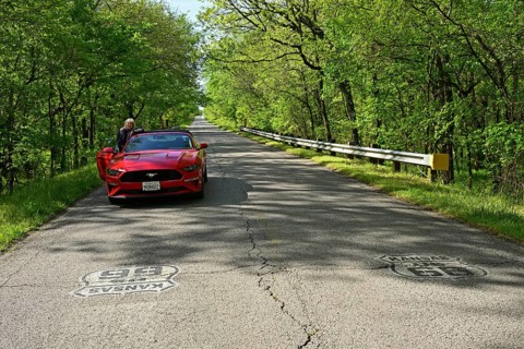 Red Ford Mustang parked on historic Route 66 in the middle of a forest in Kansas
