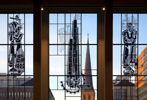 View through the glass front of the main railway station with three pictorial stained glass windows