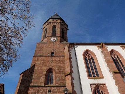 Traditional tower and half-timbered house surrounded by trees under a blue sky, historic