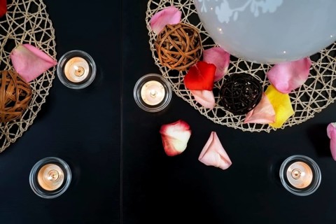 Table decoration with candles, wicker balls and rose petals