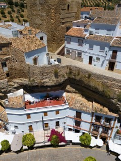 Close-up of houses integrated between rock walls with a terrace and flowering plants in the