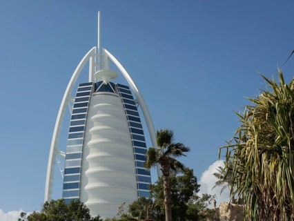 The Burj Al Arab Hotel in Dubai with palm trees and green spaces in the foreground, dubai, arab