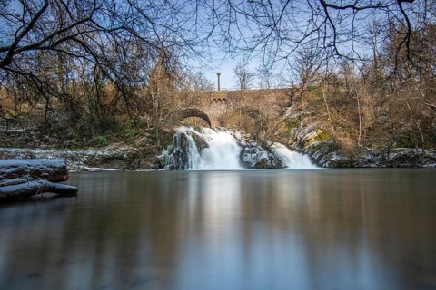 Beautiful landscape in winter with ice and snow. Waterfall of the river Elz near the castle