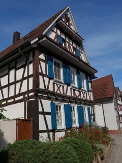 Half-timbered house with blue shutters under a clear blue sky, looks summery, historic