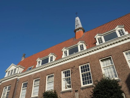 Brick building with white windows and a turret under a clear sky, Haarlem, Netherlands
