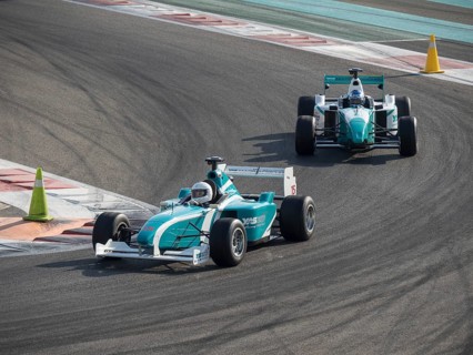 Two racing cars speed through a curve on the race track, tarmac under their wheels in competition,