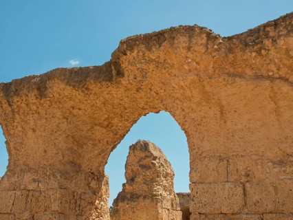 Ancient stone ruins with a large arch, blue sky in the background, Tunis in Africa with ruins from