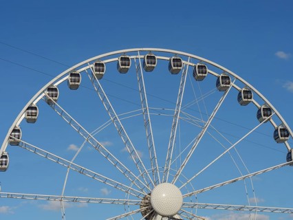 Close-up of a Ferris wheel in front of a clear blue sky, the beach of scheveningen with pier and