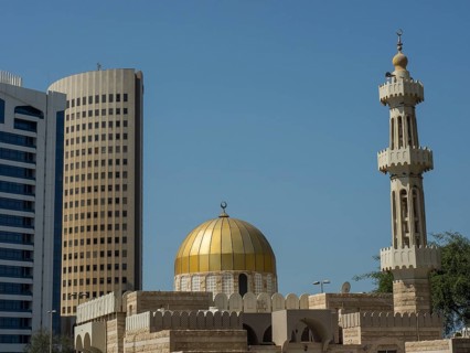 Islamic mosque with golden dome and minaret in front of modern skyscrapers, Abu Dhabi, United Arab
