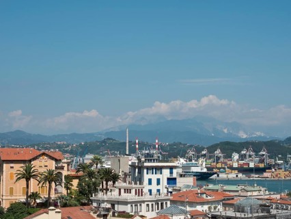 Panoramic view of a city with harbour, mountains and industrial buildings in the background under a