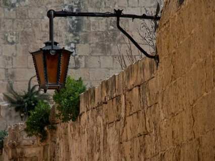 Old lantern on a traditional stone wall with some vegetation, the village of mdina on the island of