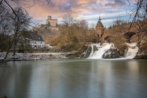 Beautiful landscape in winter with ice and snow. Waterfall of the river Elz near the castle