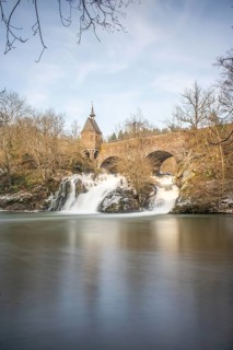 Beautiful landscape in winter with ice and snow. Waterfall of the river Elz near the castle