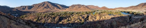 Panorama, Kunene River with green vegetation in dry red mountain landscape, waterfall and African
