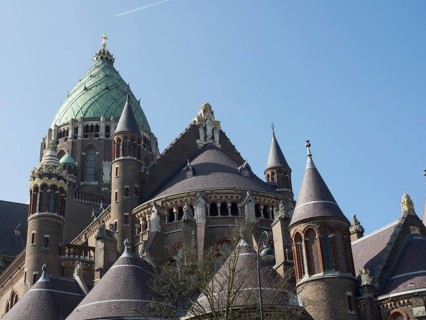 An impressive cathedral with a green dome and Gothic architecture under a blue sky, Haarlem,