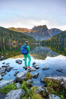 Hiker at the lake, mountain peaks of the Oetztal Alps are reflected in Lake Piburger See, in