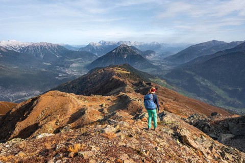 Mountaineer on Kreuzjoch summit, view of Tschirgant summit and the Oberinntal and Pitztal valleys,
