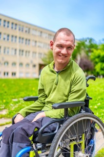 Vertical close-up portrait of a man with cerebral palsy smiling in wheelchair in the university