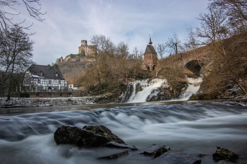 Beautiful landscape in winter with ice and snow. Waterfall of the river Elz near the castle