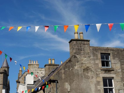 Old village houses with colourful pennants on a sunny day with a bright blue sky, grey houses with