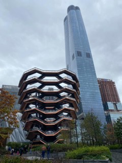 Modern building with unique architecture and skyscraper in the background on a cloudy day, people