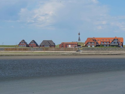 Coastal landscape with several houses along the beach and sea, under blue sky, Baltrum Germany