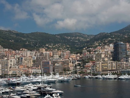 Panorama of harbour and city with many yachts and skyscrapers in front of a mountainous landscape,