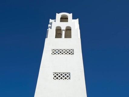 A white bell tower in minimalist style against a bright blue sky, The volcanic island of Santorini