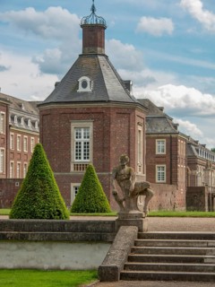 Historic castle with stone statue and steps, surrounded by trees, historic castle with a green park