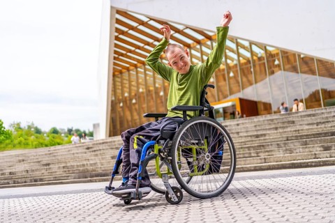 Disabled man in wheelchair celebrating raising arms proud to be in the university