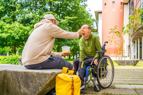 Disabled university student with cerebral palsy eating with a friend in the campus
