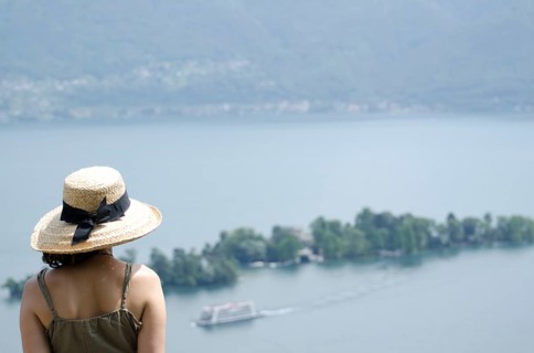 Woman with a Straw Hat Enjoy the Panoramic View over Brissago Islands and Passenger Ship on Lake