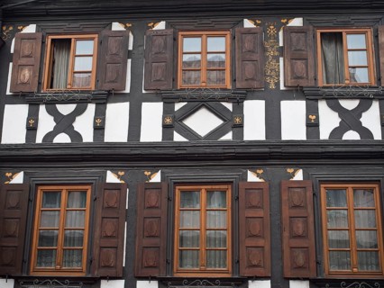 Traditional half-timbered house with dark wood structure and brown shutters in symmetrical design,