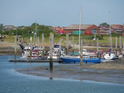 Harbour with sailing boats and houses on the shore under a clear blue summer sky, Baltrum Germany