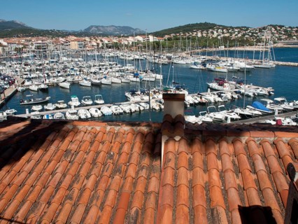 View from a rooftop onto a busy marina with many boats and houses on the hillside, la seyne sur