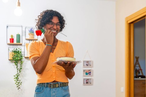 Gay man with cake and rose on the mouth trying to surprise his couple at home