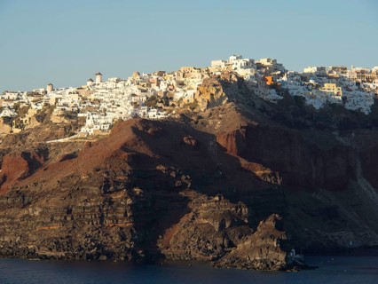 White houses on a rocky hill by the sea with a subtle evening mood in Greece, brown volcanic island