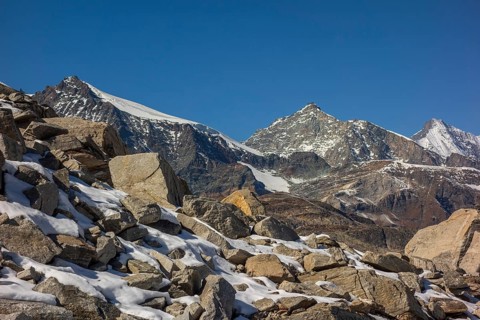 Striking mountain peaks and rock formations covered with snow under a bright blue sky, bare