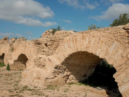 Massive, ancient stone arches of a city wall under a clear blue sky bear witness to past history,