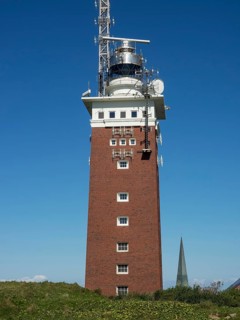 High brick lighthouse under blue sky with technical superstructures, Heligoland, Germany, Europe
