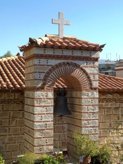 Small church with a bell and cross above surrounded by plants under a clear sky, Ancient buildings