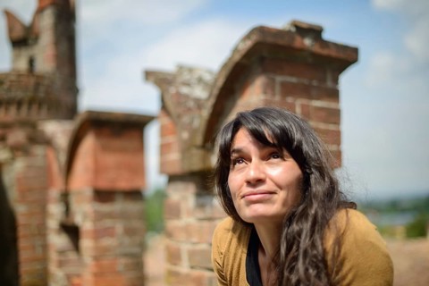 Thoughtful latino young woman sits on an old brick wall, casually dressed, enjoying a peaceful