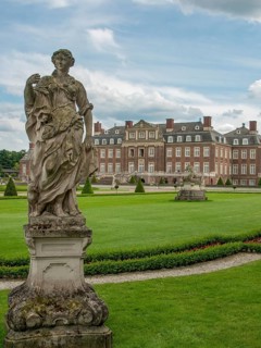 Stone sculpture in an elegant garden with a large castle in the background and cloudy sky, historic