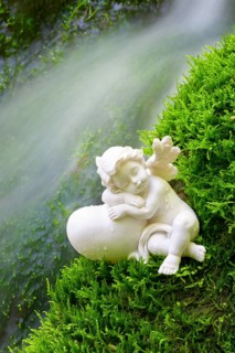 Porcelain angel figurine on moss by a waterfall